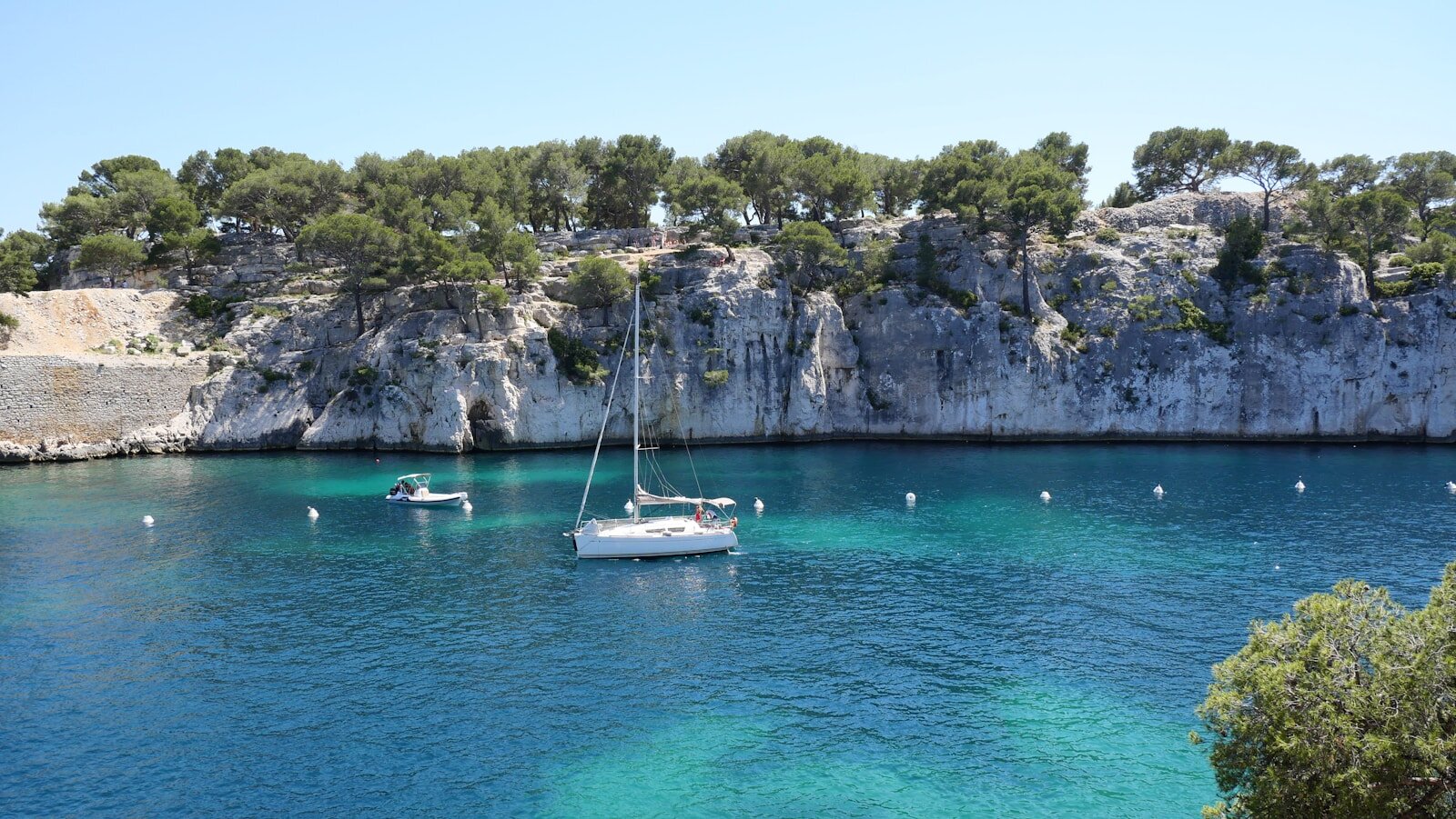 white boat on blue sea near gray rock formation during daytime